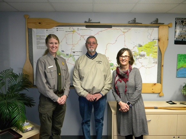 Bill Magness donation photo of 3 people standing in front of large map