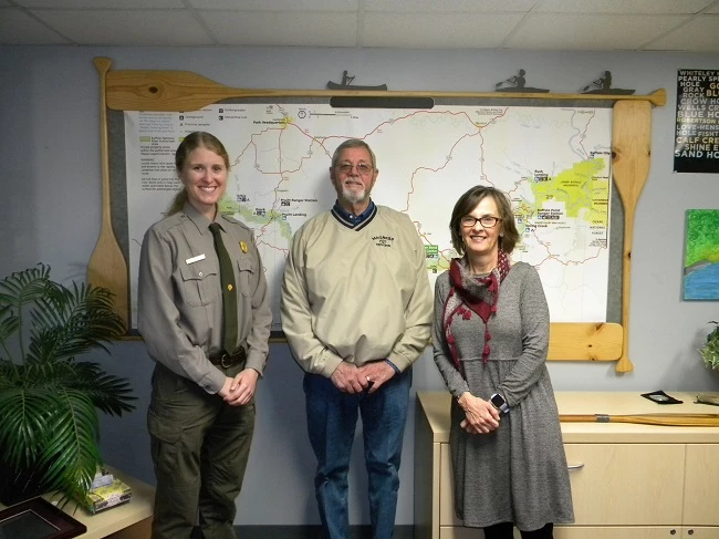 Bill Magness donation photo of 3 people standing in front of large map