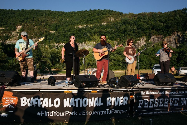 NPR on stage 2018 tfphoto Five people on a stage playing instruments with tree covered mountain in background