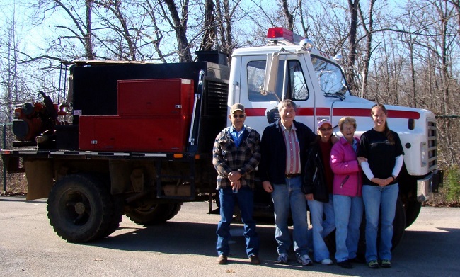 NPS Fire Truck color photo of five people posed in front of red and white fire truck