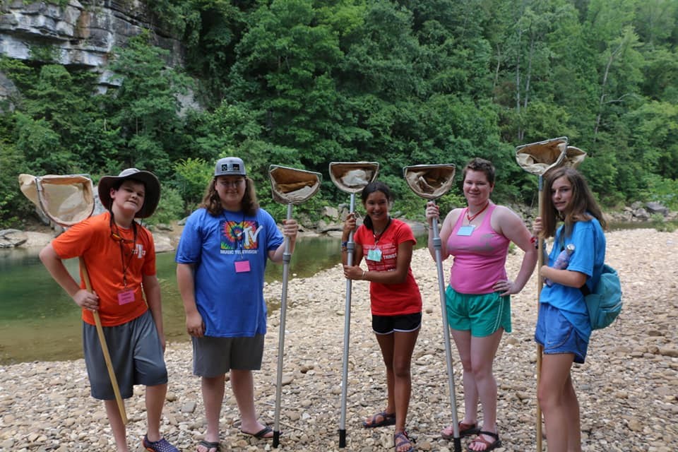 STEM campers color photo of five people standing on rocks holding large nets