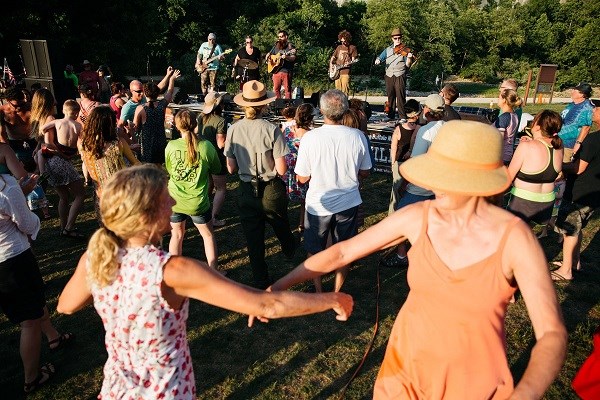 people dancing in foreground and middle with band on stage at background