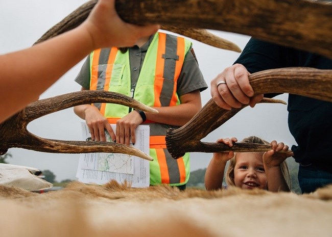 elk antlers at info station 102017 photo of elk antlers with hands holding them for small child at bottom right