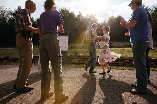 Man and woman demonstrate dance while visitors watch.