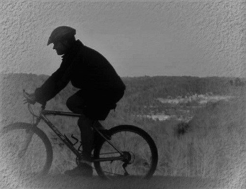 black & white photo of mountain biker on ridge overlooking valley