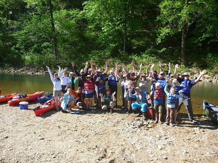 group of volunteers wearing life jackets at edge of river