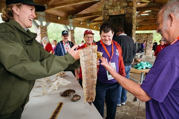 Special Olympics Fun Day participant examine a snakeskin Ranger Lauren Ray at left holding cured snakeskin