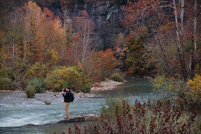 Man taking a photo of the river at Steel Creek