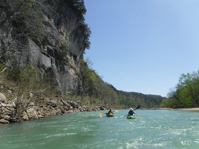 Two distant kayakers paddle around the left side of Arnold Island.