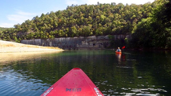 We paddle downriver with a steep gravel bar on our left and a streaked bluff on our right.