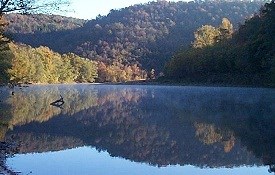 color photo of river reflecting autumn trees and bluffs in mirror images
