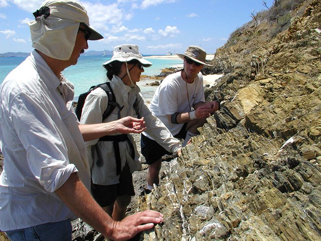 Geologists in the field discussing the rock formations on Buck