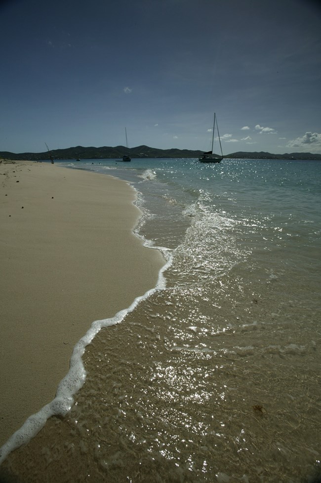 sunlight sparkling on the water receding from the beach at Buck Island