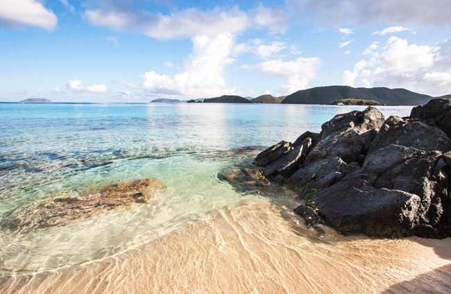 calm waters on sandy beach and rocks at Little Cinnamon Bay
