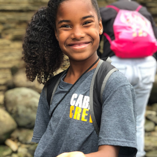 An EcoLogik camper stands in Cabrillo’s tidepools with a big smile and an outstretched hand: in the palm of her hand is a Blueband Hermit Crab.