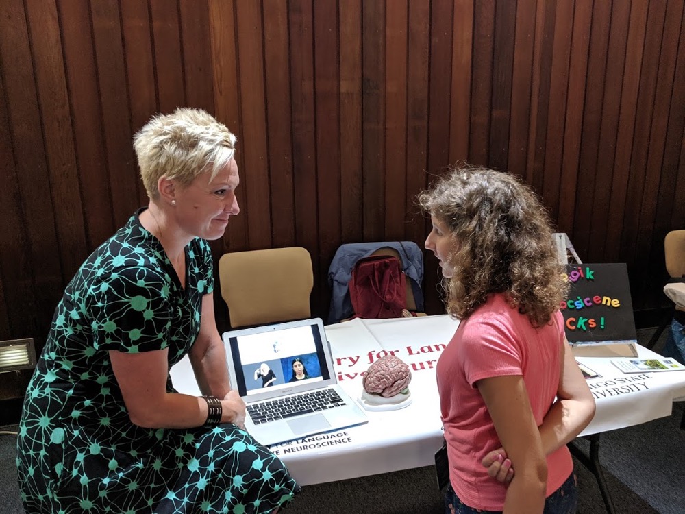 A female neuroscientist is engaged in a deep conversation about the brain with an EcoLogik camper during the Women in STEM Fair.