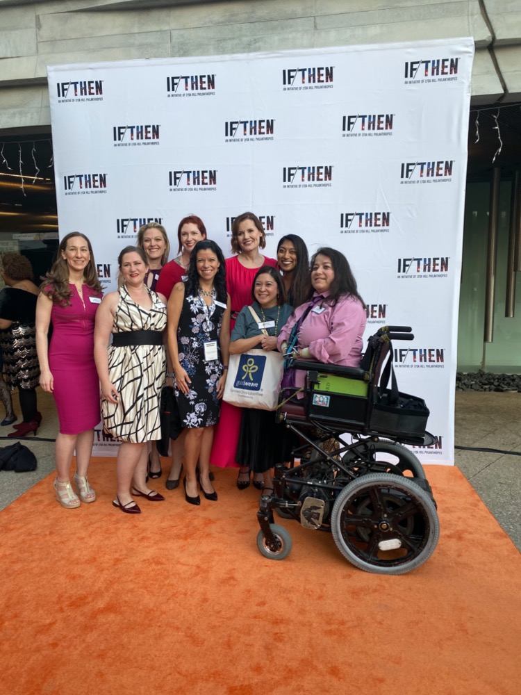 A group of women in cocktail attire pose in front of the IF/THEN® step-and-repeat. Standing in the back is actress and STEM advocate Geena Davis alongside scientist Samantha Wynns.