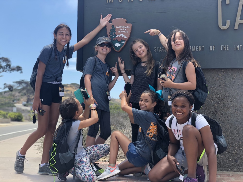 EcoLogik Project Summer Program June 2018 participants pointing to the National Park Service Arrowhead.