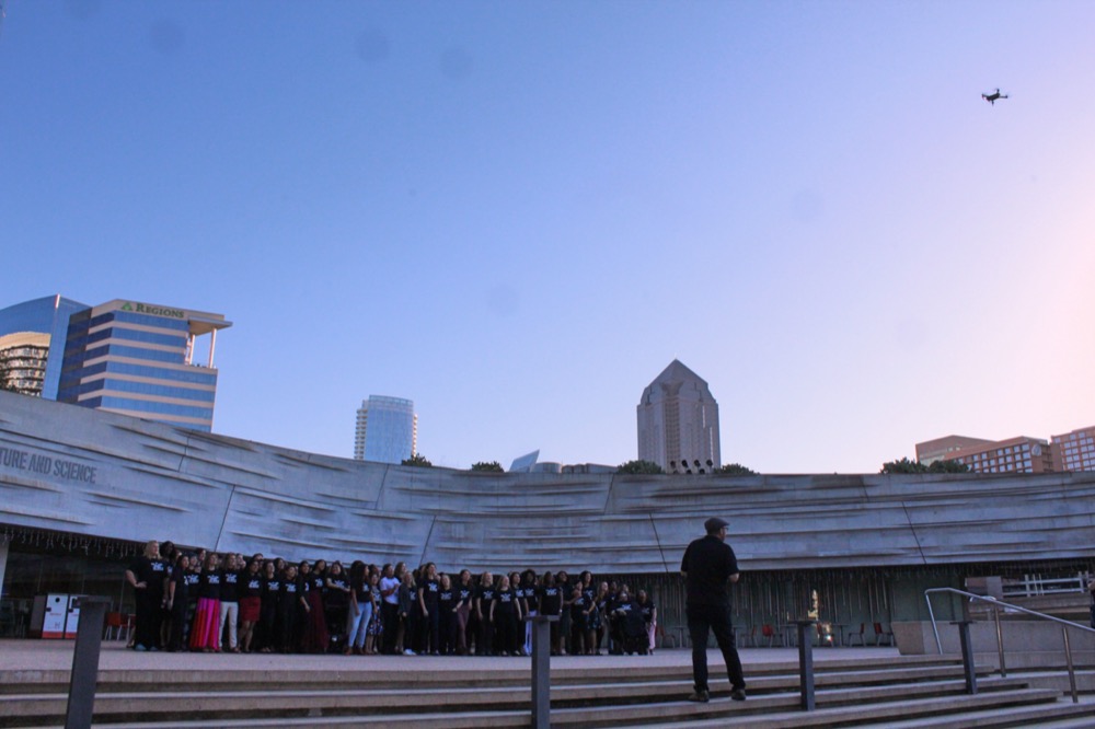 The 125 IF/THEN® Ambassadors gather on the steps to the Perot Museum in Dallas to take a group shot. In the upper right corner is the drone-photographer. Each woman is wearing her black “She can change the world” t-shirt.