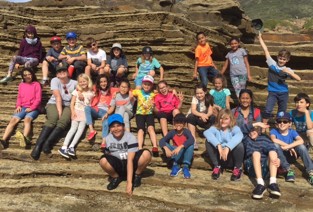 Ranger Alex sits with the happy students of a school group at the edge of CNM’s tidepools.