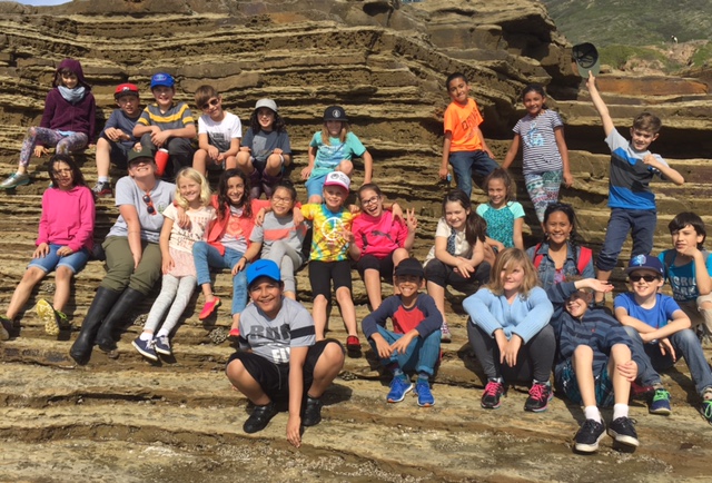 Ranger Alex sits with the happy students of a school group at the edge of CNM’s tidepools. Ranger Alex sits with the happy students of a school group at the edge of CNM’s tidepools.