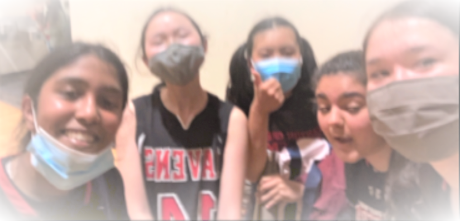 A group of 5 youth in black and red basketball jerseys pose for a picture. Some wear facemasks, and one gives a “thumbs up” to the camera.
