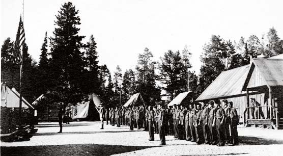men lined up to salute the flag after a day’s work at Jenny Lake CCC Camp in Grand Teton National Park, 1936.