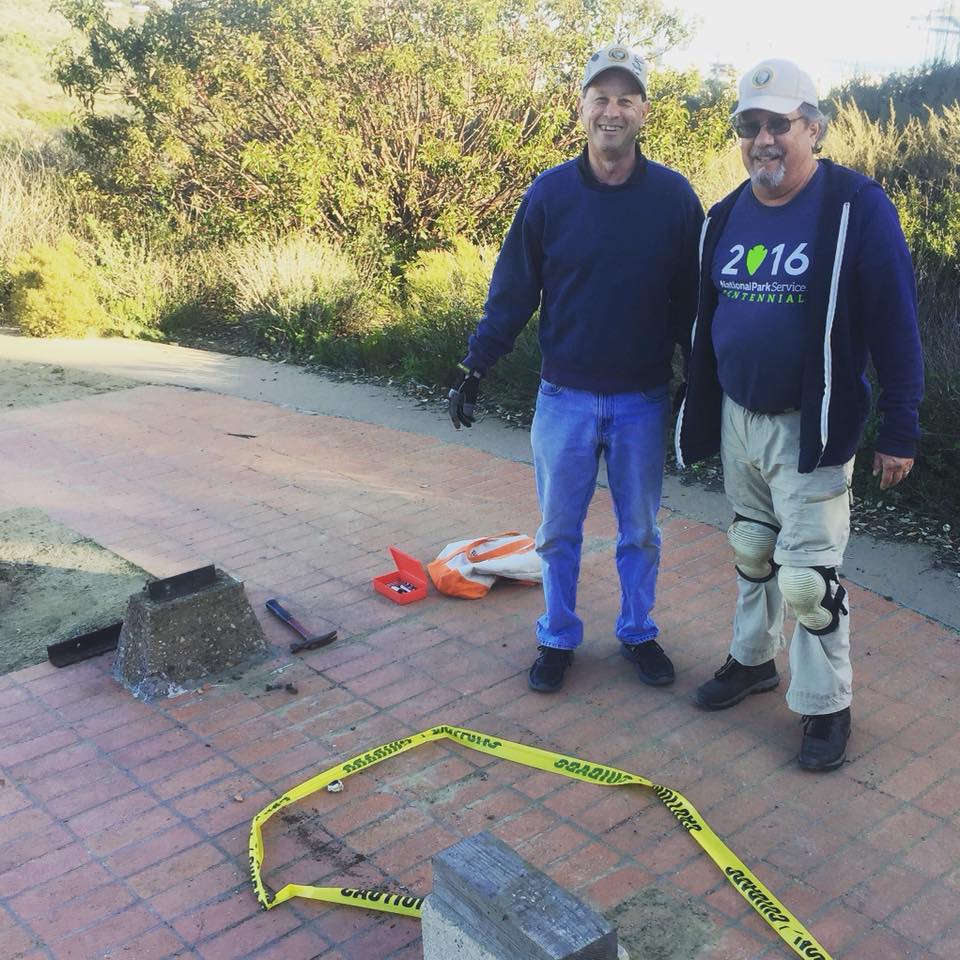 two volunteers smiling for the camera near a bench they are working on. two volunteers smiling for the camera near a bench they are working on.