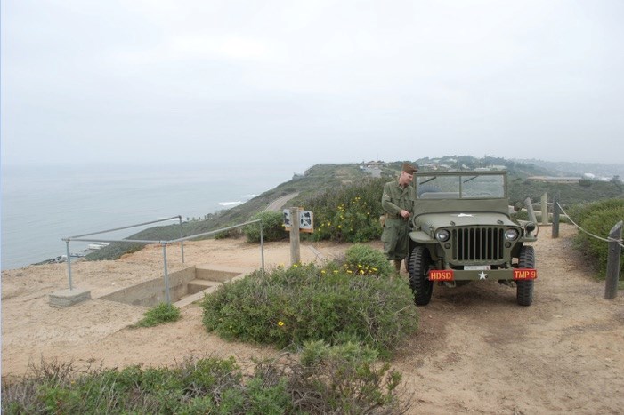 Volunteer in WWII clothing by jeep at the Bunker Entrance