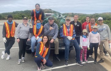 A group of people standing by a pickup truck. Some are wearing safety vests.