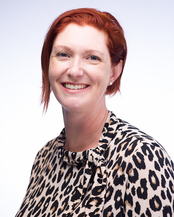 Headshot of smiling woman with short, red hair who wears a leopard-print blouse.