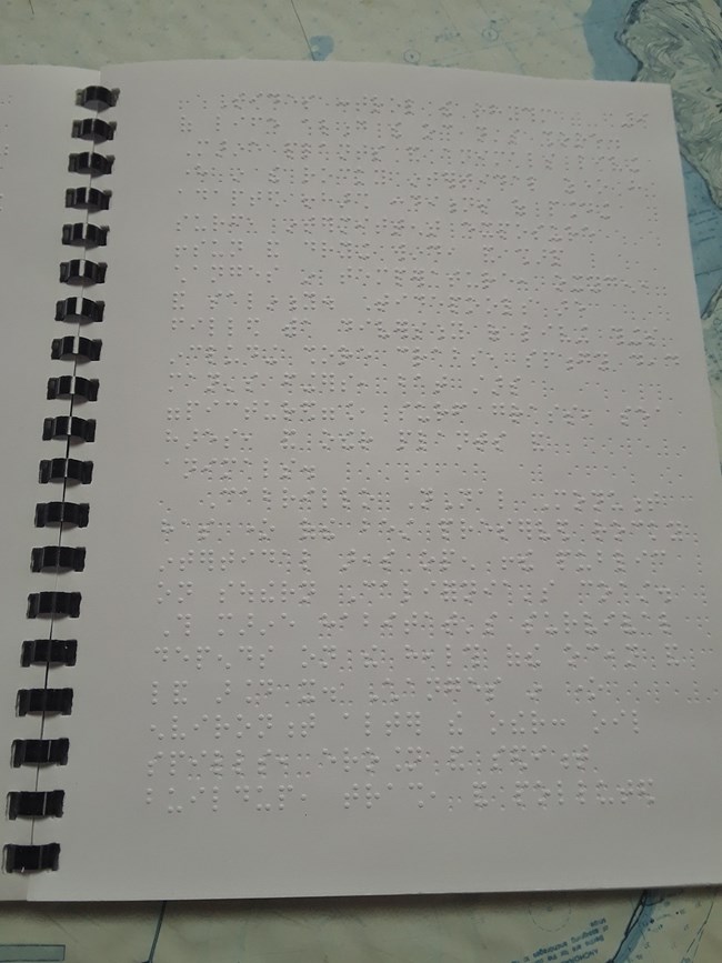 1 page full of braille dots in white spiral-bound book.