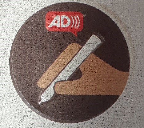 Round disc with a hand holding an electronic pen and the logo for Audio Description.