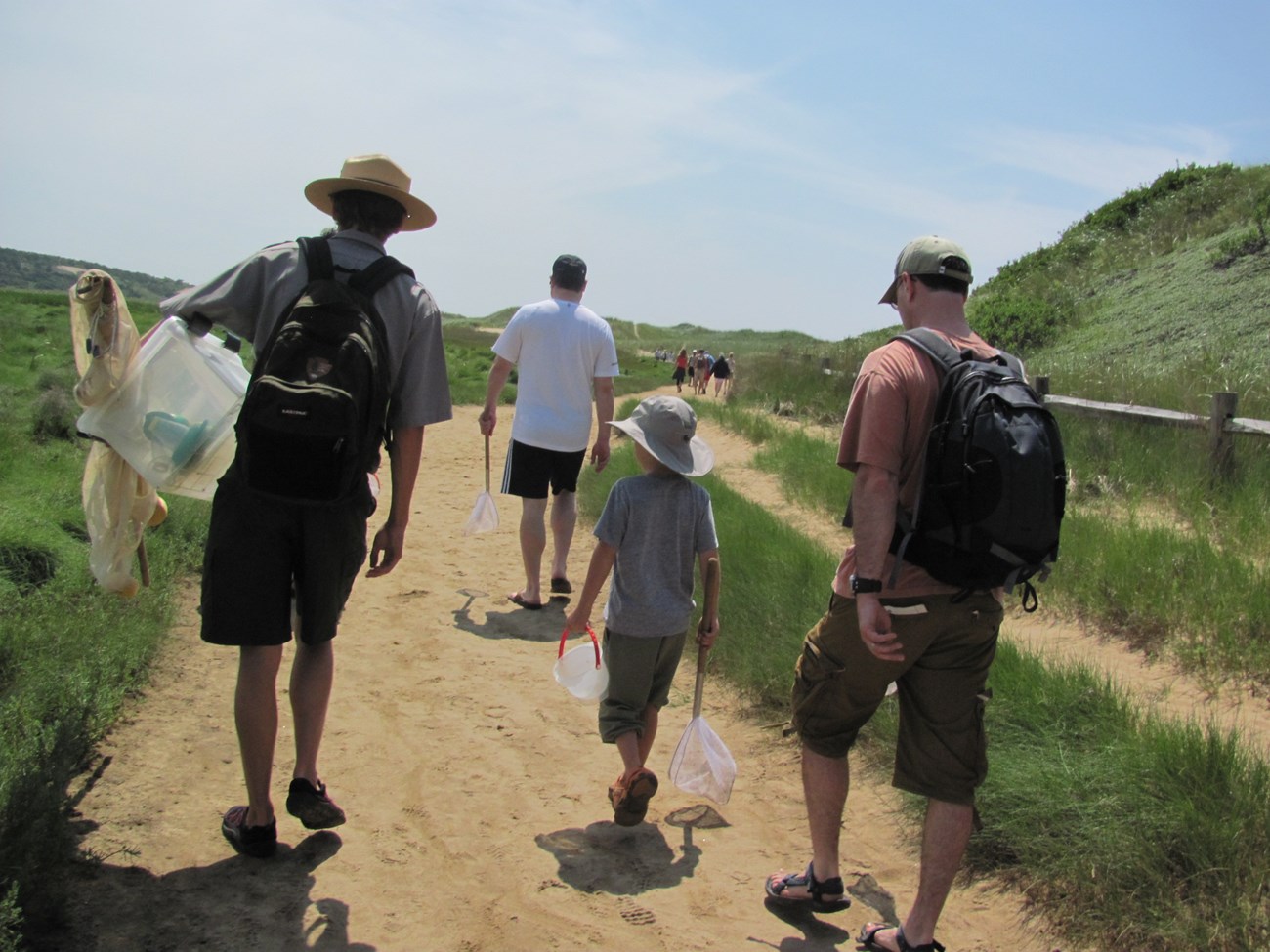 A ranger walks with a group of people along a sandy path