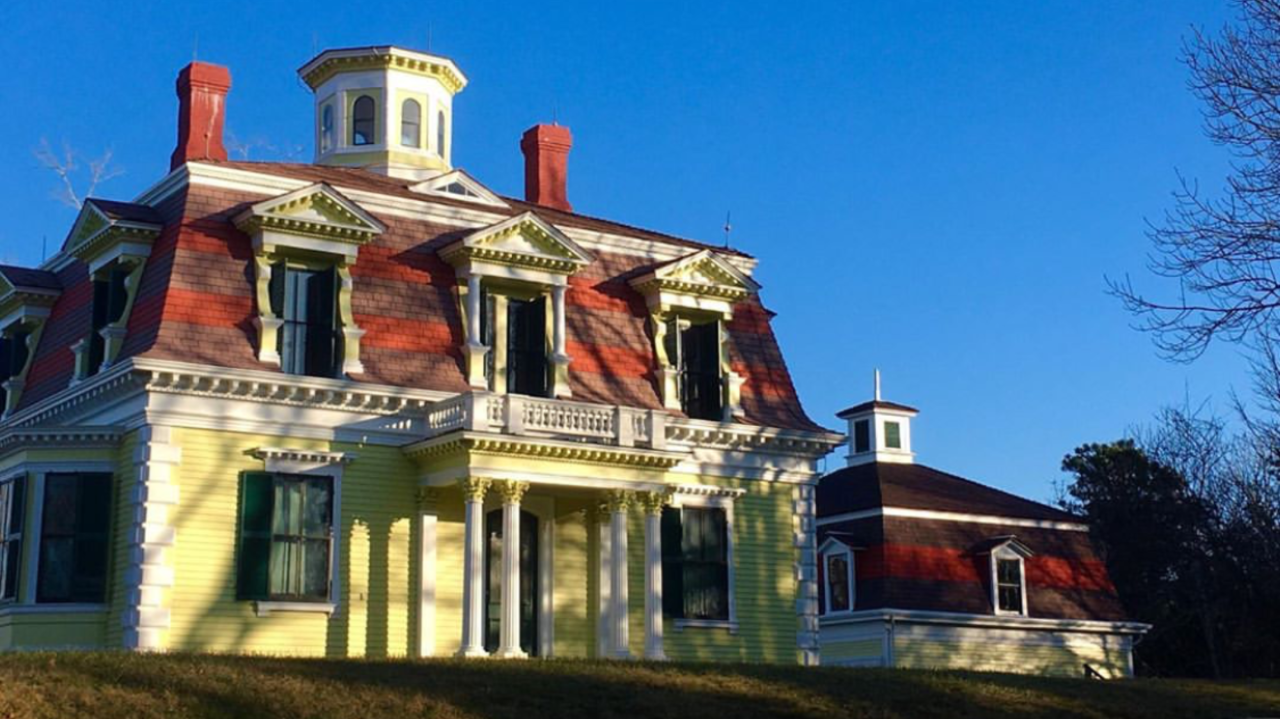 Bright yellow house with ornate features, red roof, and cupola tower