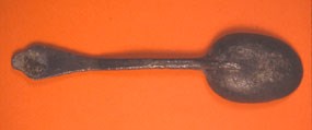 Great Island Tavern spoon. A rusted spoon on a solid background.