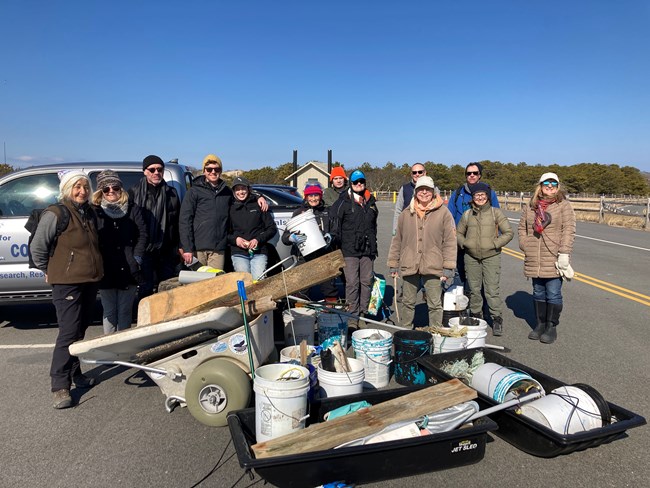 A group of people stand around tubs and carts full of marine debris.