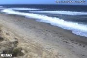 Still image of Marconi Beach. Blue waves lap up onto a sandy beach.