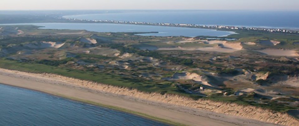 Overlooking a long peninsula with a large body of water in the middle. The close edge has a wide beach. Overlooking a long peninsula with a large body of water in the middle. The close edge has a wide beach.