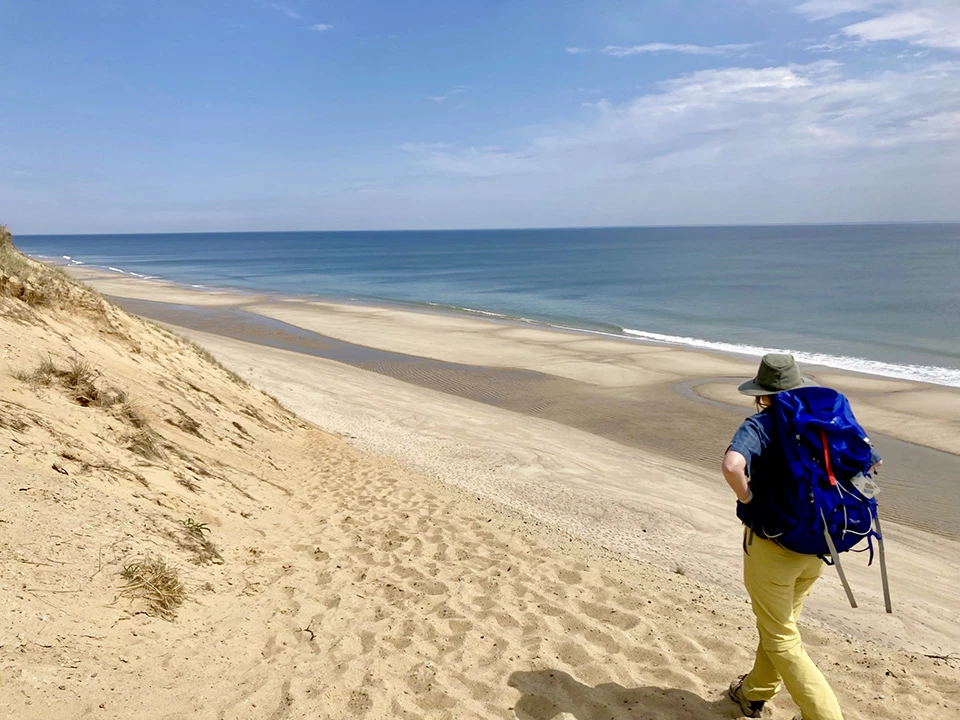 Researcher does permitted research within the Seashore. A woman walks along a beach dune with the sea visible to the right.