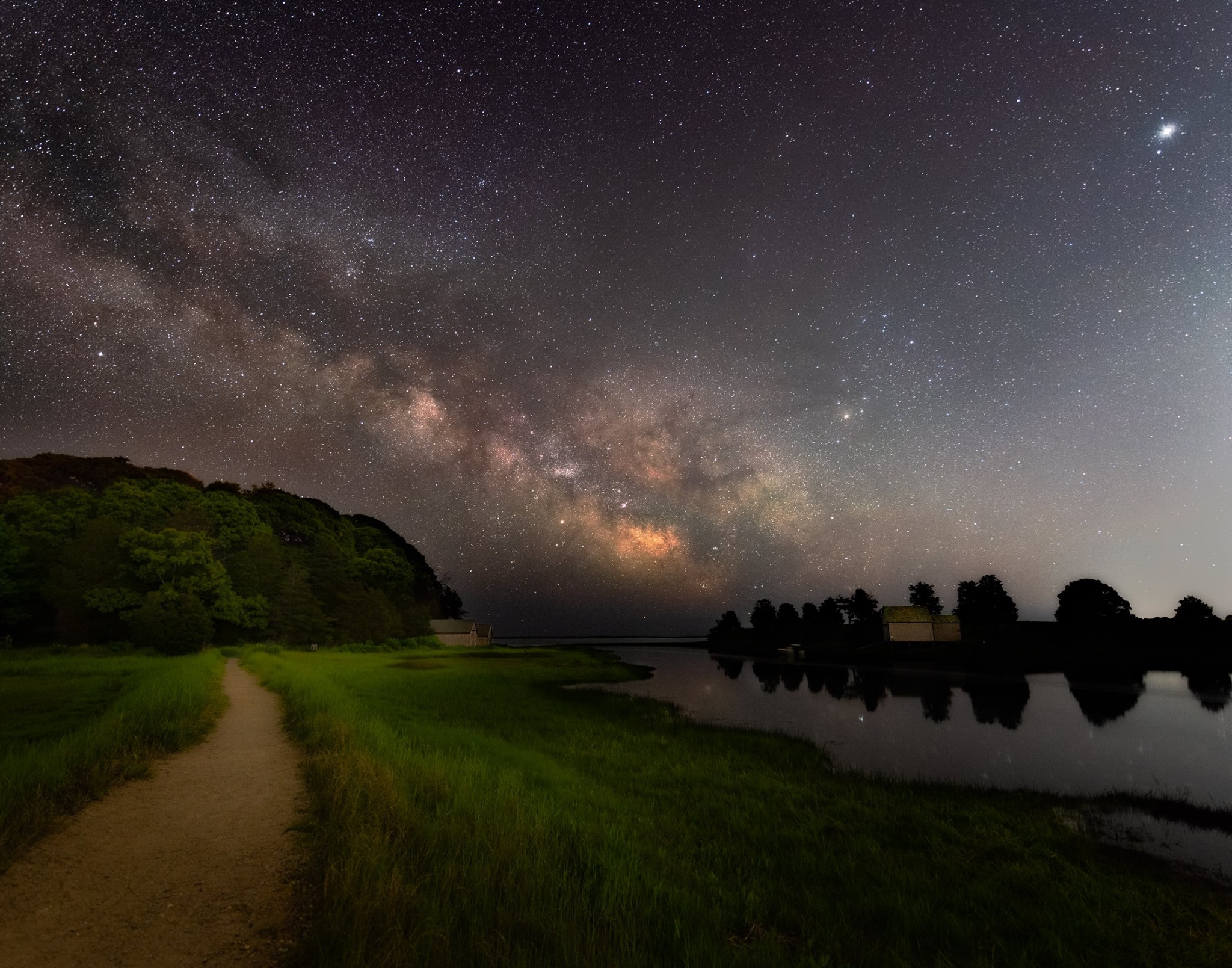 Milky Way sky over the Nauset Marsh Trail starlit night over the Nauset Marsh trail, adjacent to Salt Pond in Eastham. A trail winds through lush green grass, with a bright, starlit, Milky Way sky overhead.