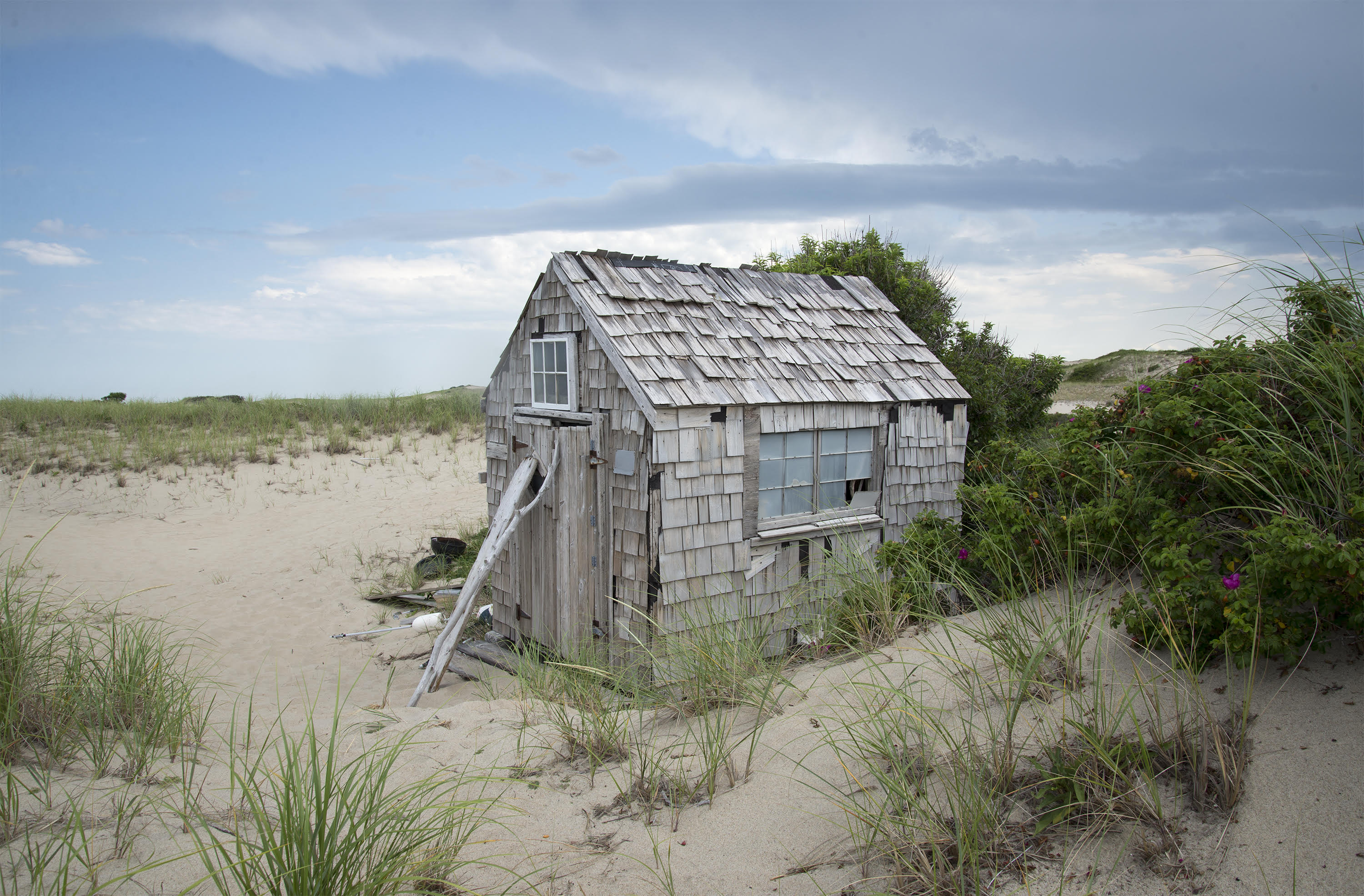 Dune Shack Photograph by Jane Paradise A small wooden shack sits in the middle of a sand dune landscape.