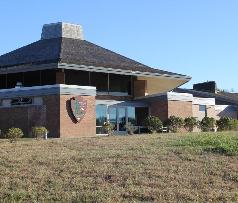 A brick and shingle building with an arrowhead sits on a hill.