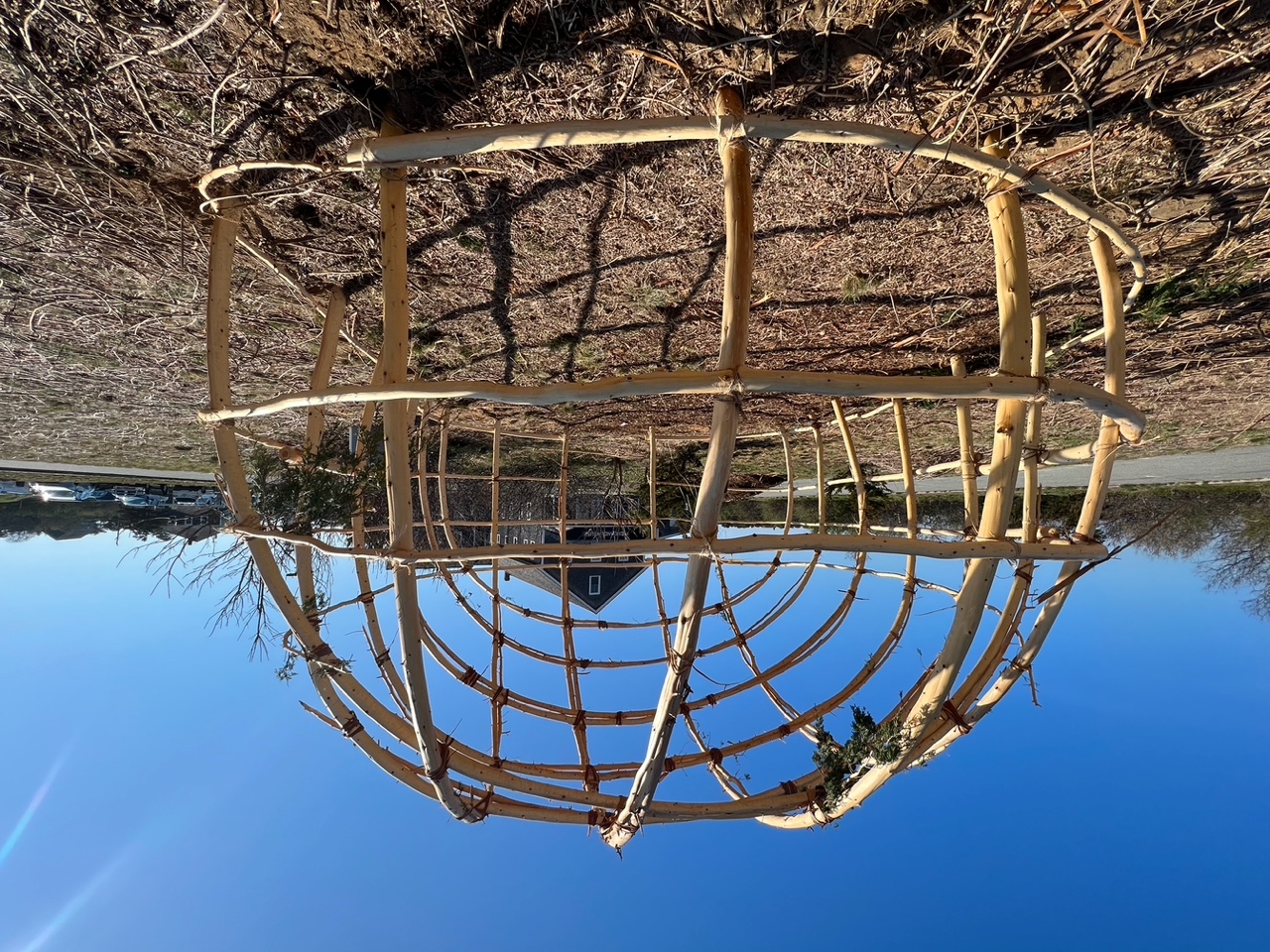 A wetu structure stands against a bright blue sky. A wetu structure stands against a bright blue sky.