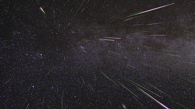 A field of stars and streaking meteors over the black darkness of space.