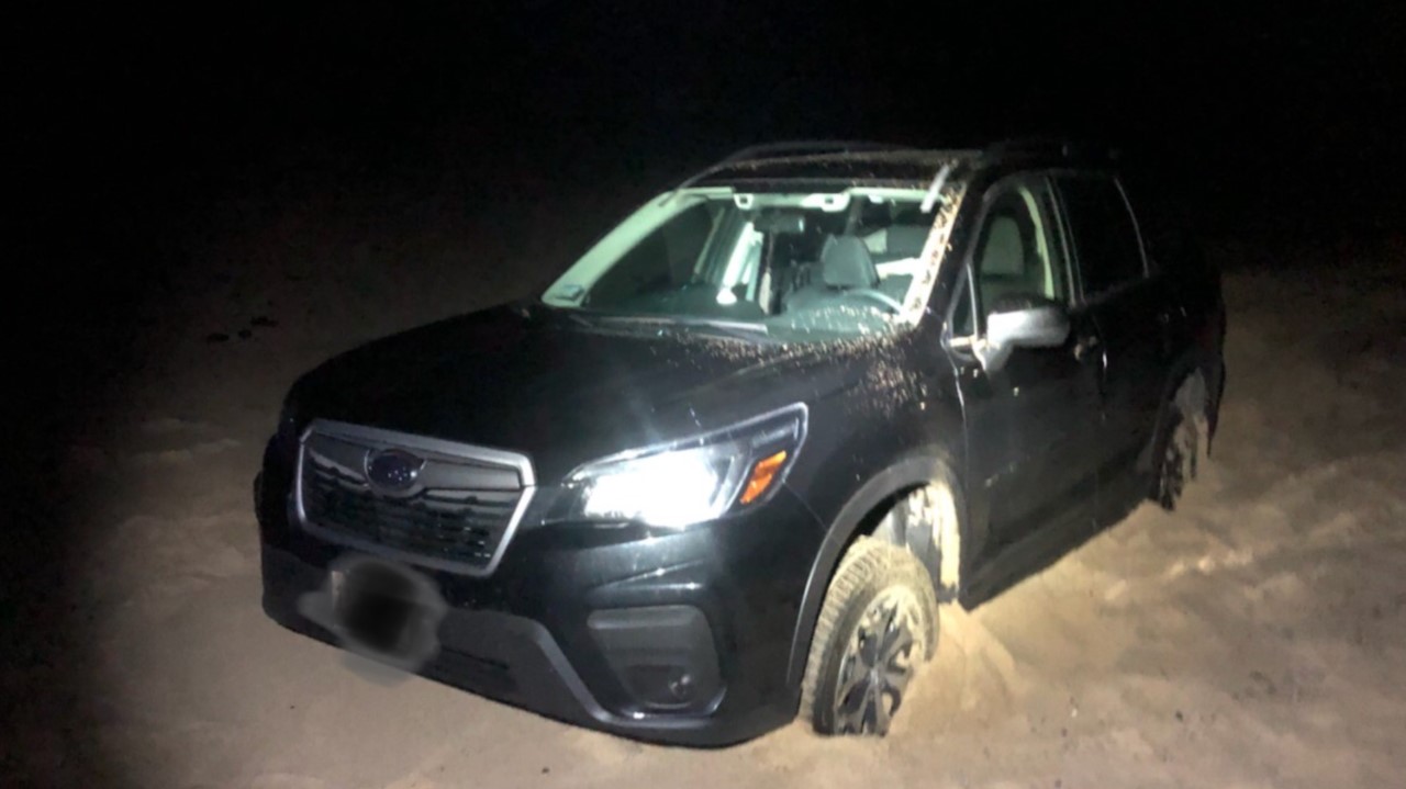 Vehicles being driven off roadways, graffiti, and vandalism cause seashore managers to encourage responsible recreation. A small, black car is stuck in the sand at night