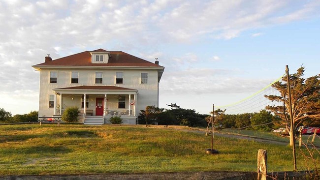 A Georgian style home with a porch sits on a hill.