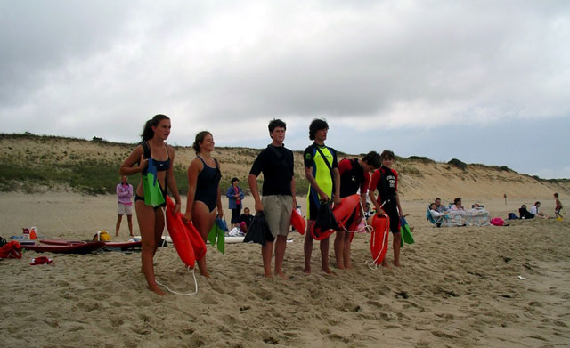 Junior Lifeguards at Cape Cod. Junior lifeguards stand ready on an overcast day on a beach to practice their skills.