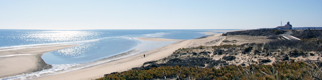 A view of a beach with a large sandbar from the view of a cliff top, a white building sets in the background. A view of a beach with a large sandbar from the view of a cliff top, a white building sets in the background.