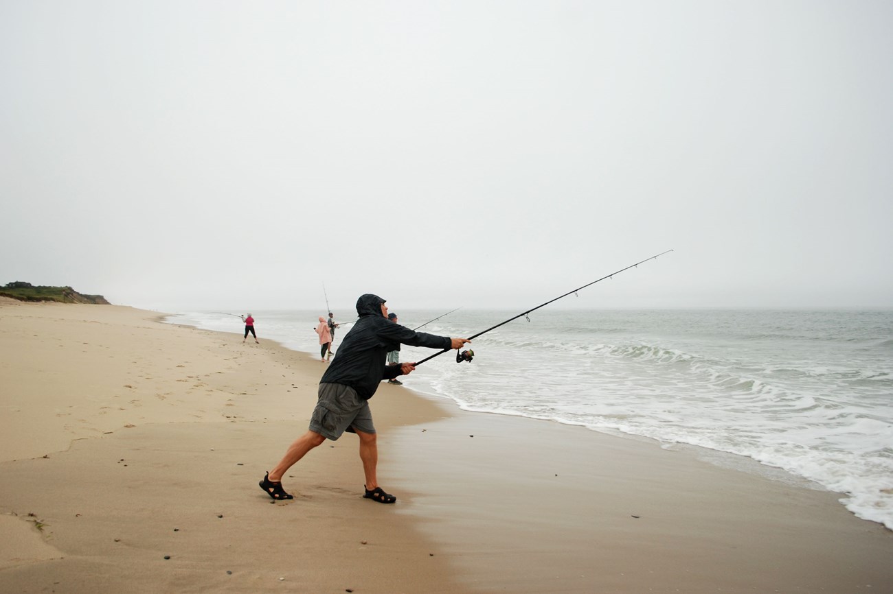 Visitor surf casts into the ocean.